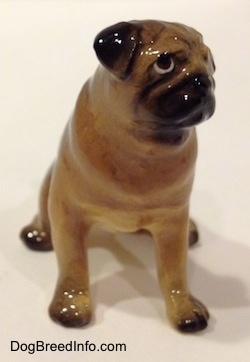A brown with black miniature Pug figurine that is seated. The figurine has black ears.