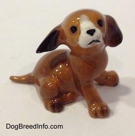 The right side of a brown with white mini puppy sitting figurine. The figurine has black circles for eyes.