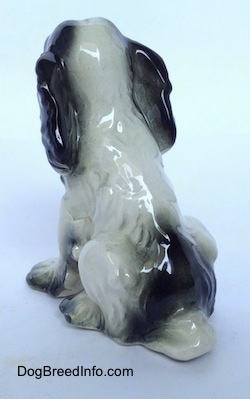 The back of a white with black Russian Spaniel dog figurine. The figurine has a black spot above its tail.