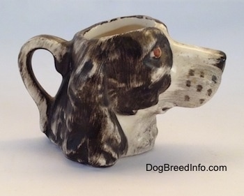 The right side of a brown and white Russian Spaniel dog stein cup. The ears are hard to see against the head of the cup.