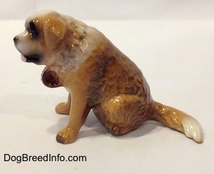 The left side of a figurine of a brown with white Saint Bernard in a sitting position. The figurine has its mouth painted open.