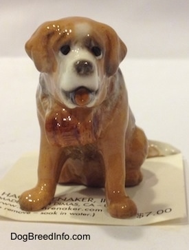 A brown with white figurine of iniature Saint Bernard. The figurine has black circles for eyes.