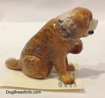 The right of a brown with white Saint Bernard sitting figurine. The figurines tail is sticking out.