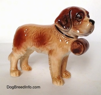 The front right side of a white with brown Saint Bernard figurine. This figurine has fine hair details along its body. 