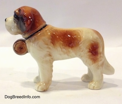 The left side of a porcelain white with brown Saint Bernard figurine. The figurine has brown spots along its left side.
