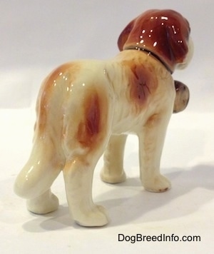 The back right side of a figurine of a white with brown Saint Bernard. The figurine is very glossy.