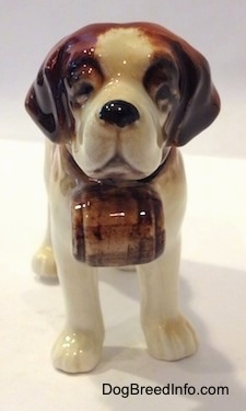 A figurine of a white with brown porcelain Saint Bernard. It is hard to see the black eyes of the figurine.
