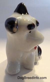 The front of a white with black bone china figurine of a Schnauzer. The figurine has black ears. One is flooped over and the other is standing.