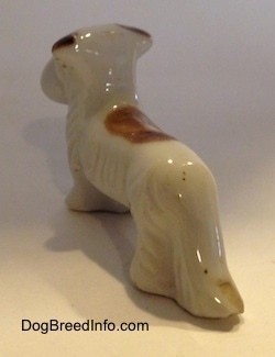 The back left side of a bone china Schnauzer figurine. The figurine has a large brown spot on its back.