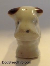 A bone china Schnauzer figurine that has black circles for eyes and a nose. 