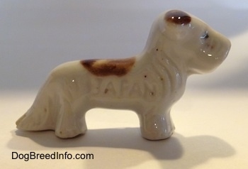 The right side of a white with brown bone china Schnauzer figurine. The figurine has fine hair details.