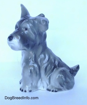 The left side of a grey and white miniature Schnauzer sitting figurine. The figurine has fine hair details.