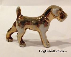 The right side of a Gold paitned bone china Schnauzer figurine. The figurine has a gold collar on.