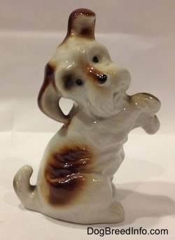 The bone china parti-colored Miniature Schnauzer in a begging position figurine. The figurine has black circles for eyes and a nose.