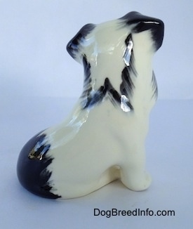 The right side of a parti-color ceramic Miniature Schnauzer sitting figurine. The figurine has a black spot above its tail.