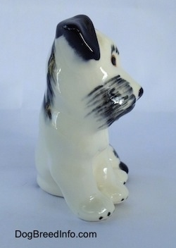 The front of a miniature parti-colored ceramic Miniature Schnauzer figurine in a sitting position.