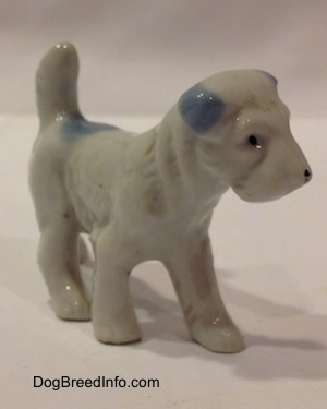 The front right side of a white with blue bone china Miniature Schnauzer standing figurine. The figurine has fine hair details.