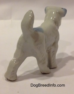 The back right side of a bone china Miniature Schnauzer standing figurine. The figurine has its long tail arched over its back.