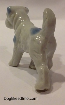The back left side of a bone china Miniature Schnauzer figurine in a standing pose. The legs of the figurine are medium length.