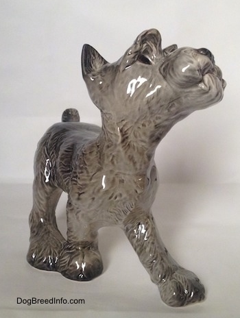 The front left side of a grey with white figurine of a Schnauzer puppy. The figurine has fine hair details.