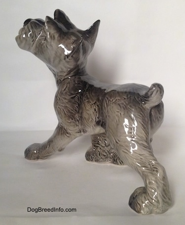 The back left side of a grey with white figurine of a Schnauzer puppy. The figurine is glossy.
