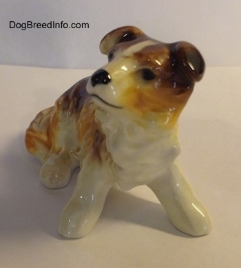 A white with brown porcelain Scotch Collie figurine sitting.