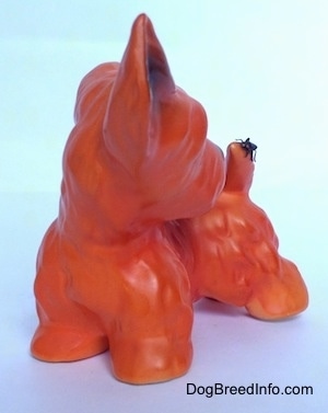 The front right side of an orange figurine of a Scottish Terrier. The figurine has a fly on it.