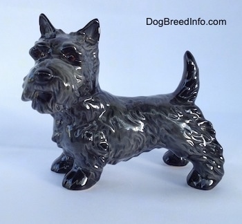 The left side of a black Scottish Terrier figurine. The figurine has fine hair details along its body and legs.