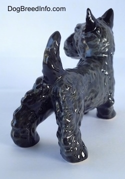 The back right side of a black figurine of a Scottish Terrier. The figurine has its perky ears.