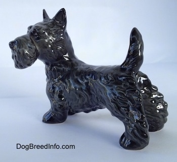 The back left side of a black Scottish Terrier figurine. The figurines body is longer than its legs.
