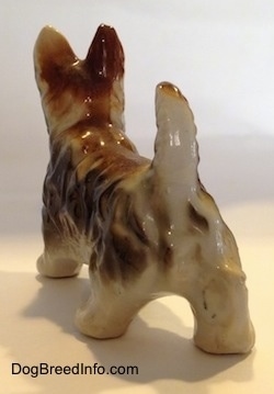 The back left side of a bone china brown with white Scottish Terrier figurine. The tail of the figurine is in the air.