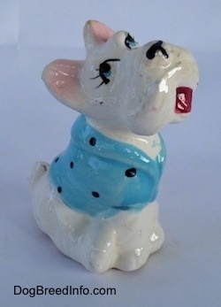 A Scottish Terrier figurine sitting with a blue with black dots shirt on. The figurine has cartoon features.