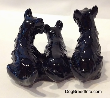 The back of a trio of black Scottish Terrier figurines.All of the figurines are in a seated position.