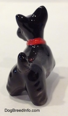 The back right side of a black figurine of a Scottish Terrier. The figurine has a short tail in the air.