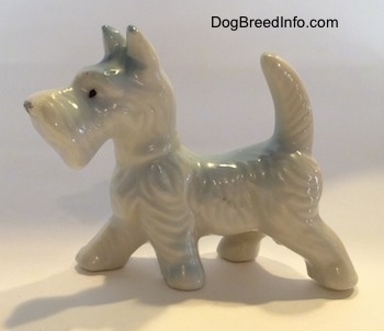 The left side of a bone china white Scottish Terrier figurine. The figurine has short legs.