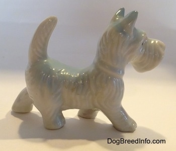 The right side of a white bone china figurine of a Scottish Terrier. The figurine has hair details along its head and back.