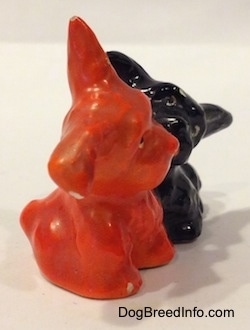 The right side of an orange figurine and a black figurine of Scottish Terriers that are playing. Both figurines are glossy.