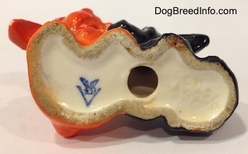 The underside of a figurine. The figurines have a hole under them and to the left of the hole is the full bee inside the V logo of Goebel W.Germany.