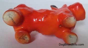The underside of an orange and black Scottish Terrier figurine. The figurine has a stamp on its back paws. There is the Stamp of Germany and the full bee inside the v logo of Goebel W.Germany.