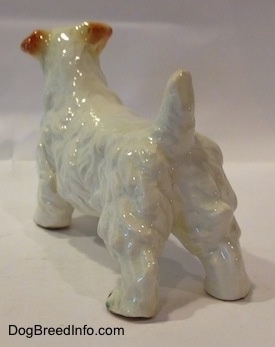 The back left side of a figurine of a white Sealyham Terrier. The figurine has its short tail in the air.