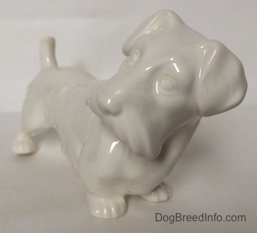 The front right side of a white unpainted Sealyhan Terrier figurine. It is hard to see the features of the figurine.