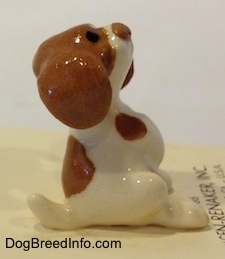 The right side of a white and brown figurine of a Miniature Curbstone Setter puppy figurine in a begging pose. The figurine has black circles for eyes.