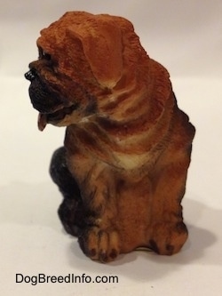 A black with brown Shar-Pei puppy figurine that is in a sitting position. The ears of the figurine is hard to differentiate from its head.