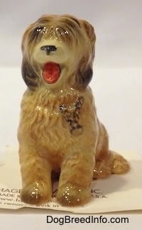 A tan with brown Sheepdog figurine that is in a sitting pose. The figurine has its mouth painted open.