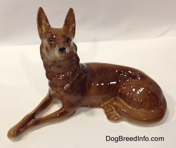 The left side of a brown with white Shepherd figurine. The figurine has thin front legs.