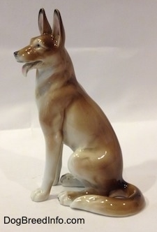 The side of a brown and white figurine of a German Shepherd sitting.