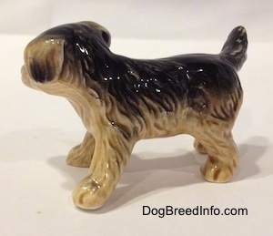 The right side of a black with tan figurine of a German Shepherd puppy. The figurine has small paws.