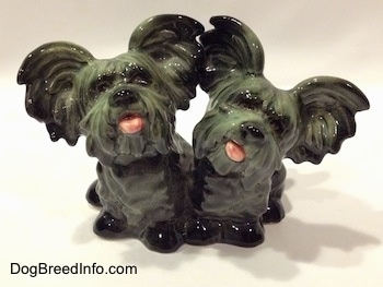The front of a Siamese twin Skye Terrier figurine. The figurines tongues are out.