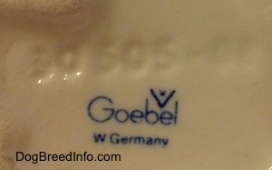 Close up - The underside of a Siamese twin Skye Terrier figurine. On the underside of is the blue stamp logo of Goebel W.Germany and above it is an engraving that reads '30 505-03'.