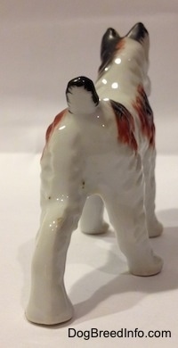 The back side of a white with brown and black porcelain Standard Schnauzer figurine. The figurine has a short black and white tail.